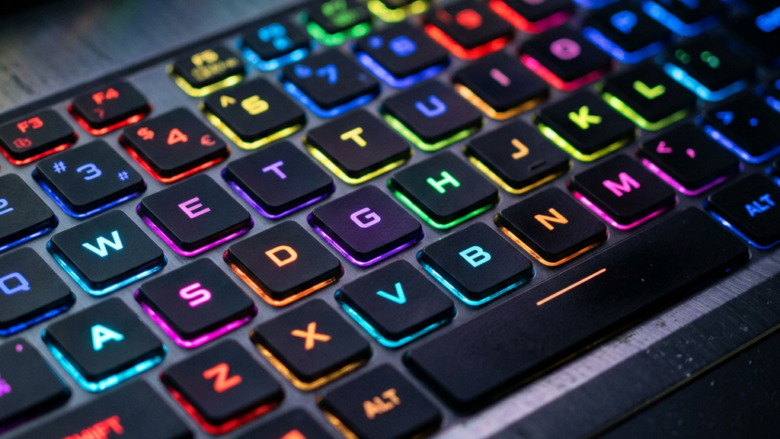 Close-up of a laptop keyboard with RGB backlighting showing keys QWERTY and surrounding keys illuminated in various colors.
